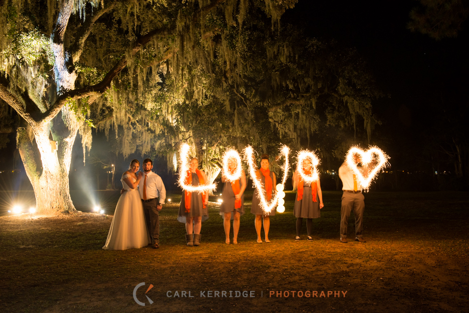 Love written in sparklers with bride and groom under live oaks at Sunnyside plantation