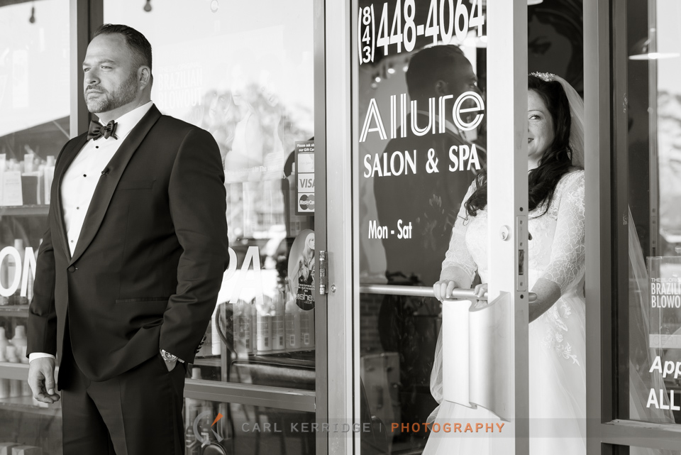 Myrtle Beach wedding, first look before the wedding, groom standing outside waiting, bride opening salon door, bride peaking at the groom