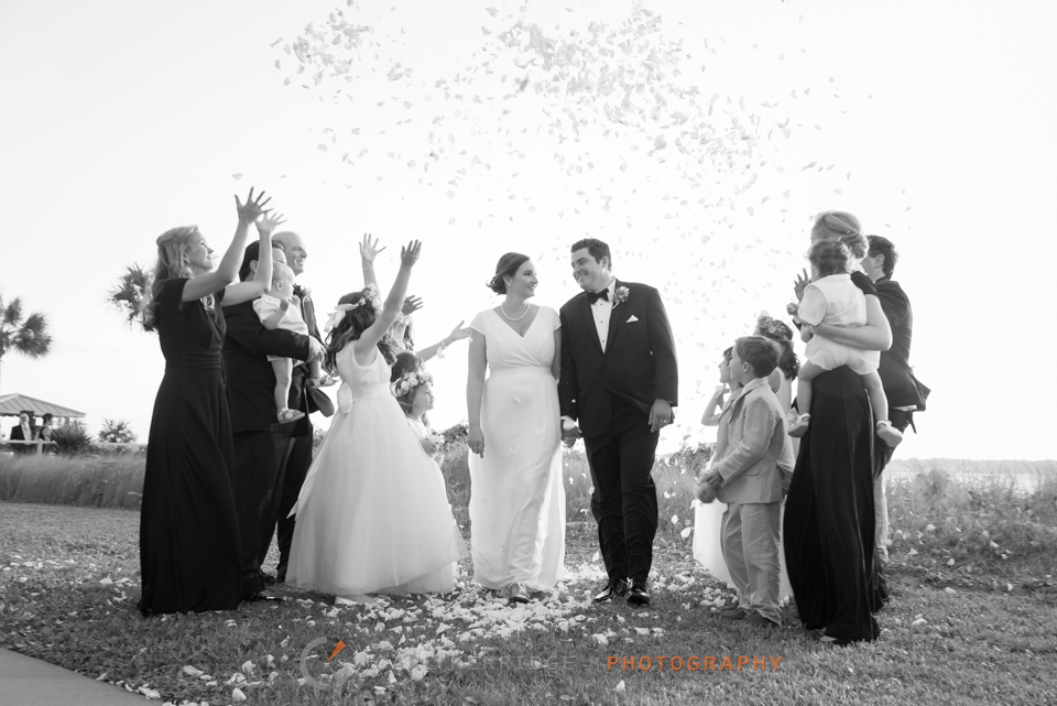 the wedding party throws flower petals over the bride and groom to celebrate the elegant wedding