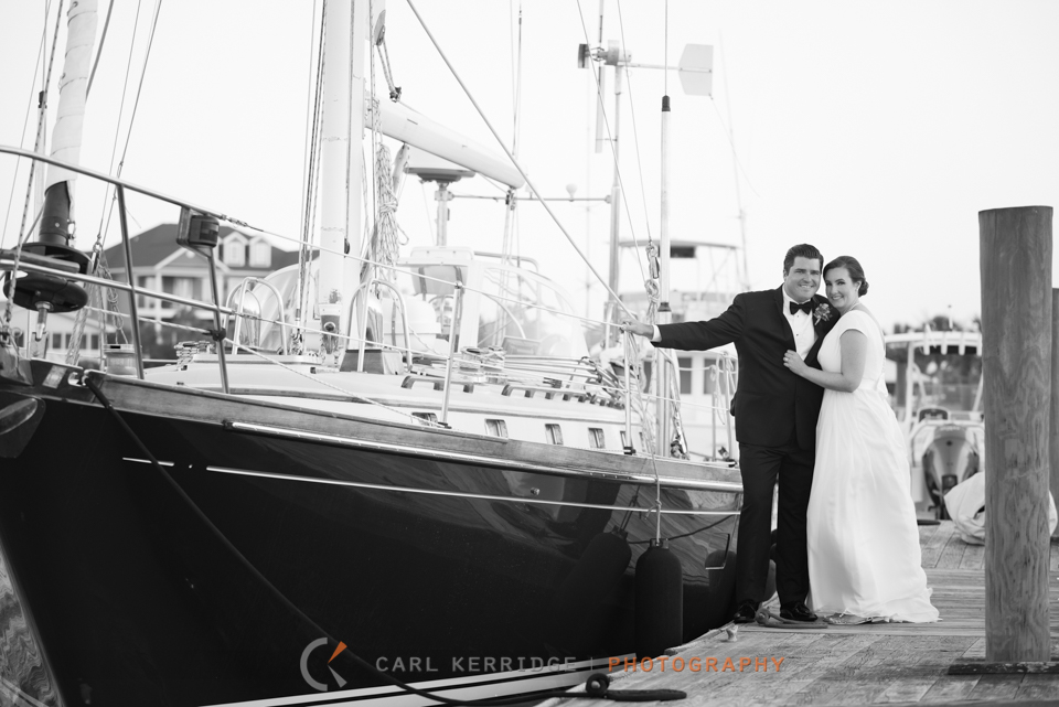 wedding couple pose for a portrait by a sail boat in murrells inlet harbor, wedding give away photo