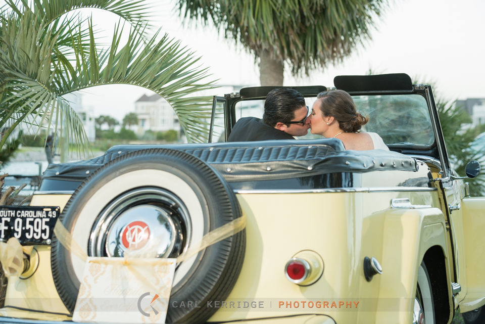 after the elegant wedding, the bride and groom share a kiss in a classic willy's jeepsters