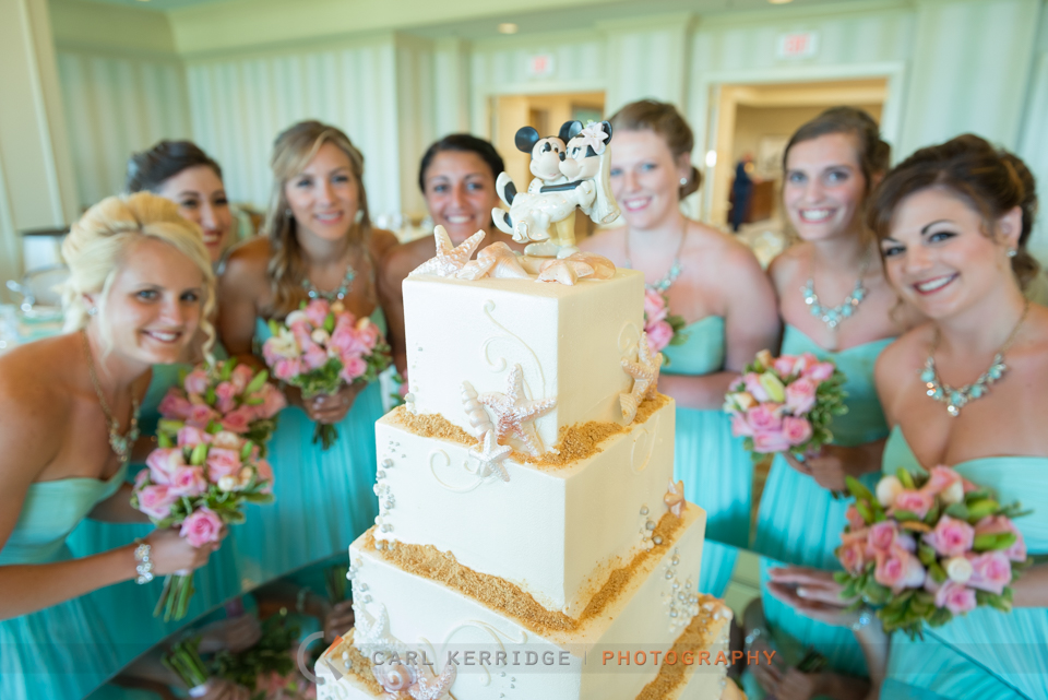 bridesmaids pose for photo behind minnie and mickey cake topper at the dunes club of myrtle beach