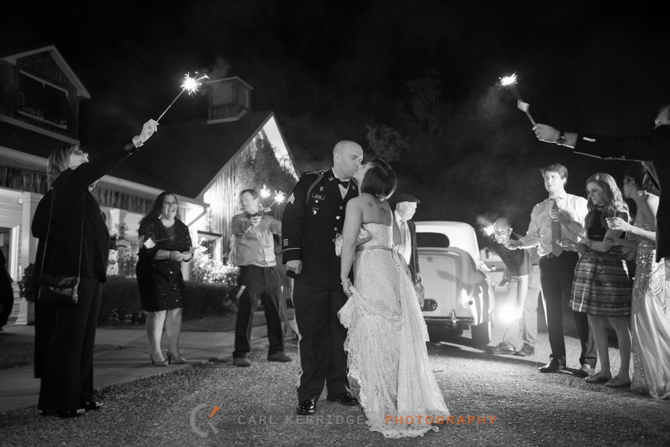 bride and groom walk out of the wedding reception and kiss after a sparkler exit