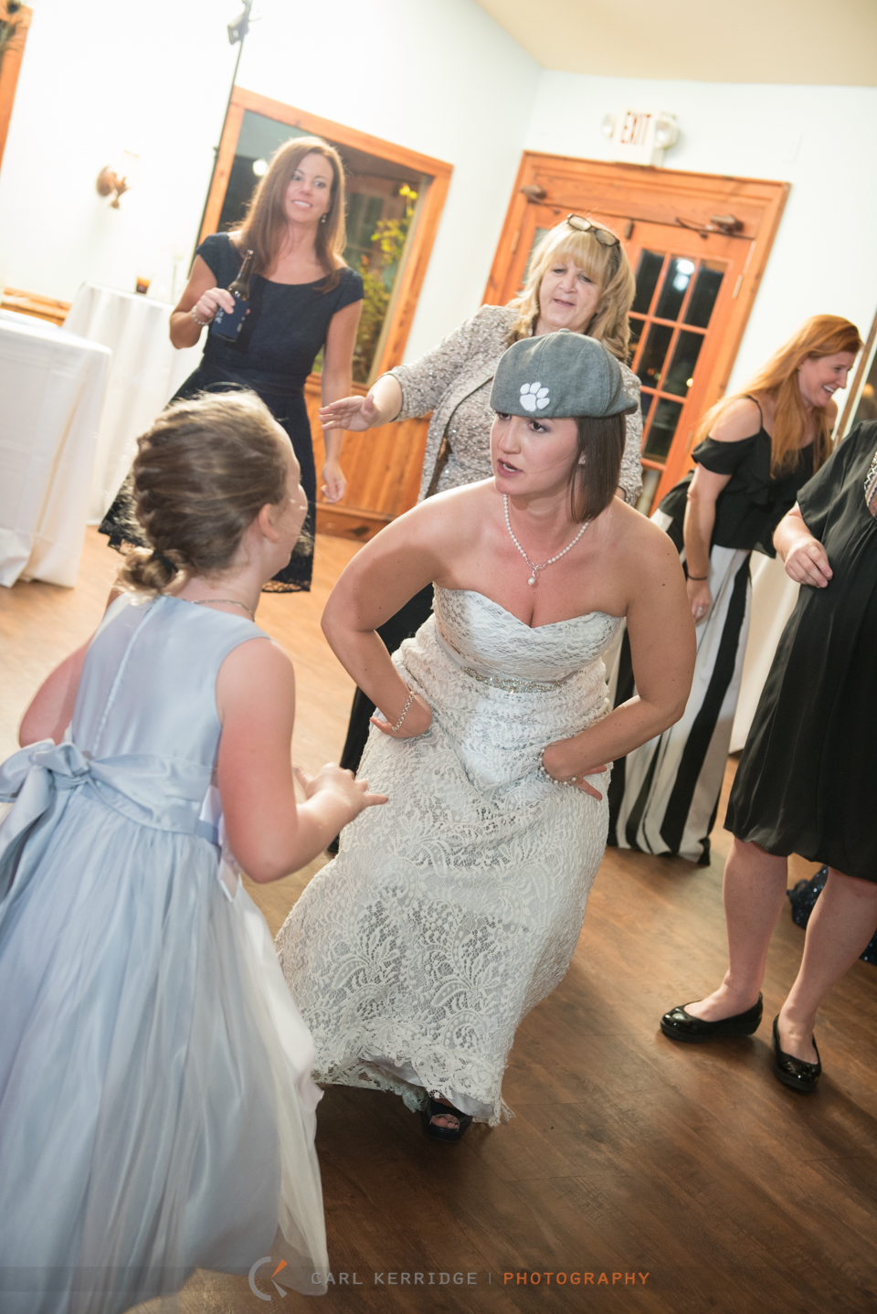 bride parties in a clemson hat at the wedding reception