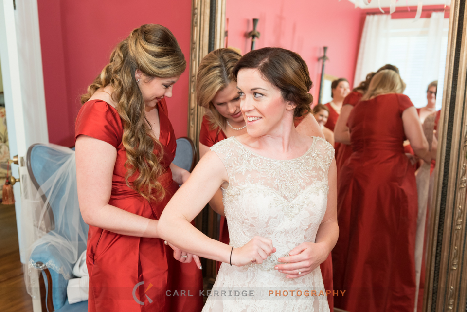 southern bride enjoys the moment as two of her bridesmaids button up her wedding dress 