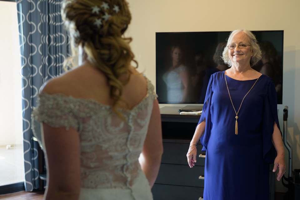 mother of the bride beams as she looks at her daughter getting ready for her myrtle beach wedding