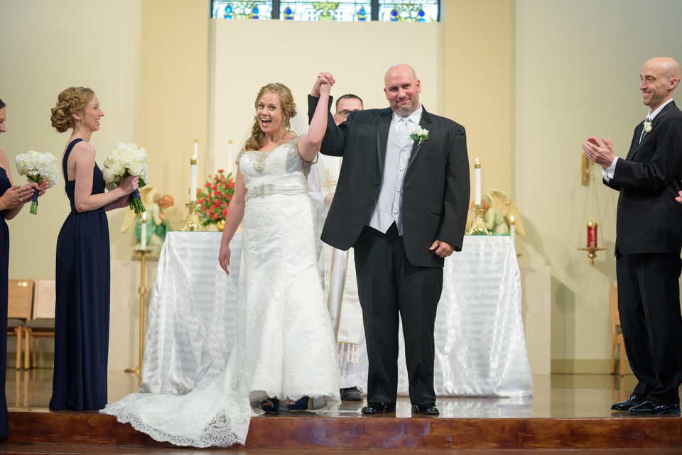 bride and groom put their hands in the air to celebrate being man and wife
