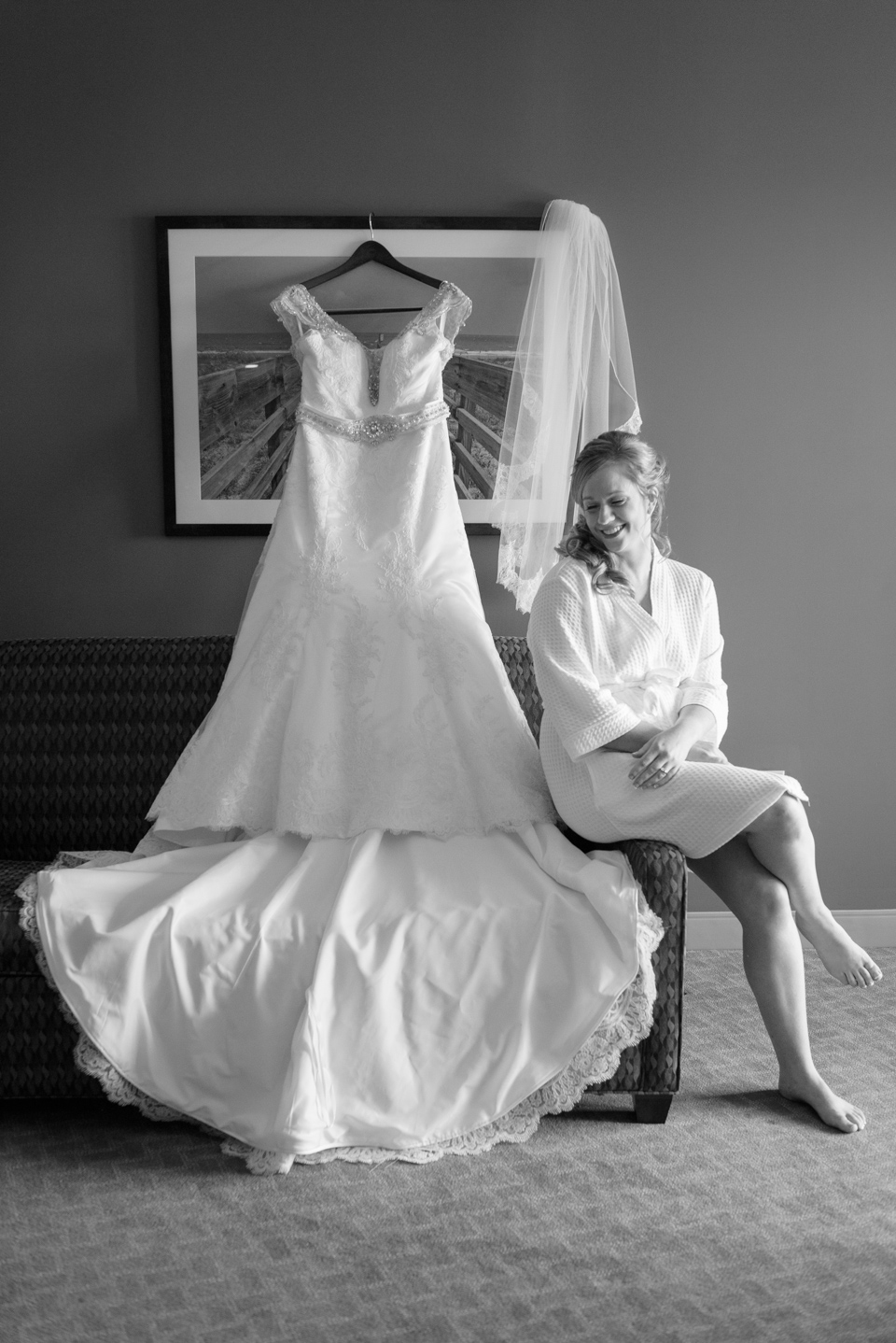 bride smiles and giggles while sitting next to her wedding dress