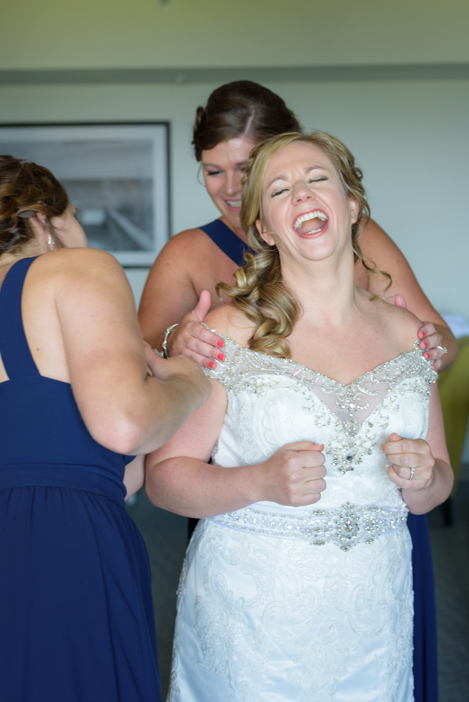 bride bursts out laughing as her bridesmaids glue on her wedding dress