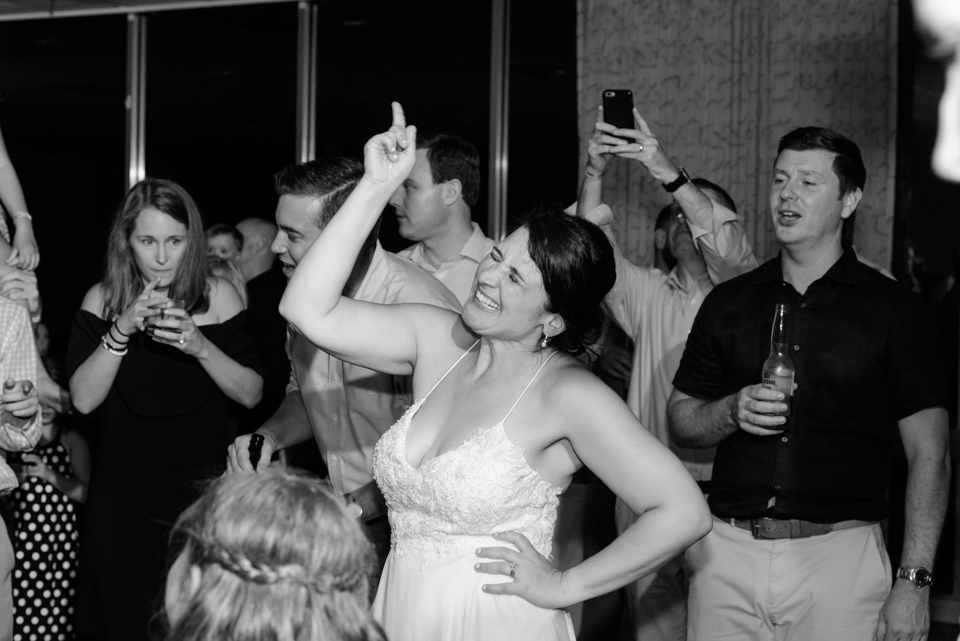 bride points up to the sky during the wedding reception