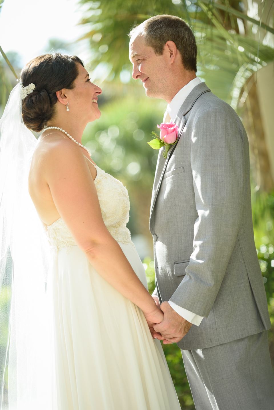 bride and groom face each other smiling and holding hands before their wedding