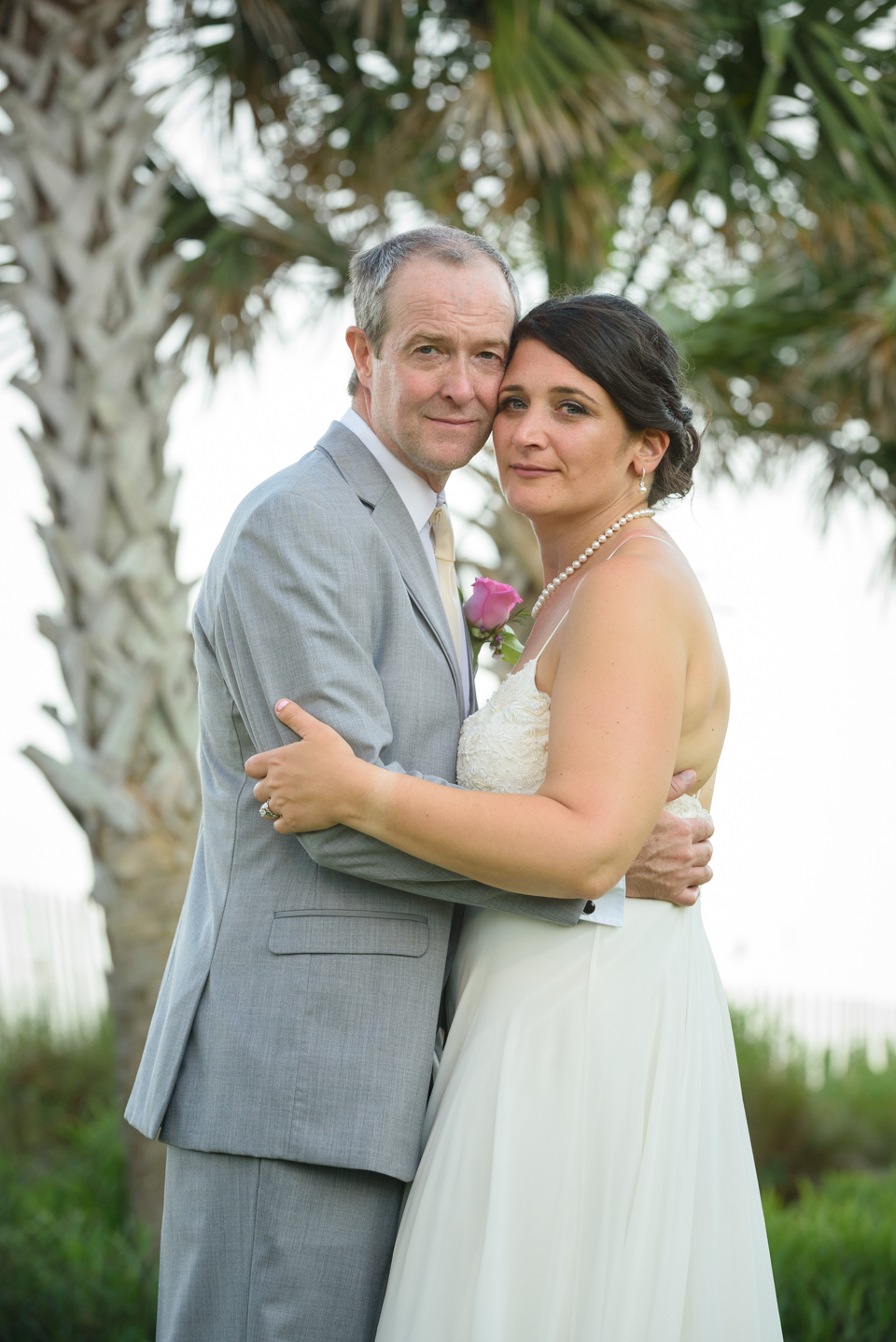 the wedding couple pose cheek to cheek for portraits at the beach
