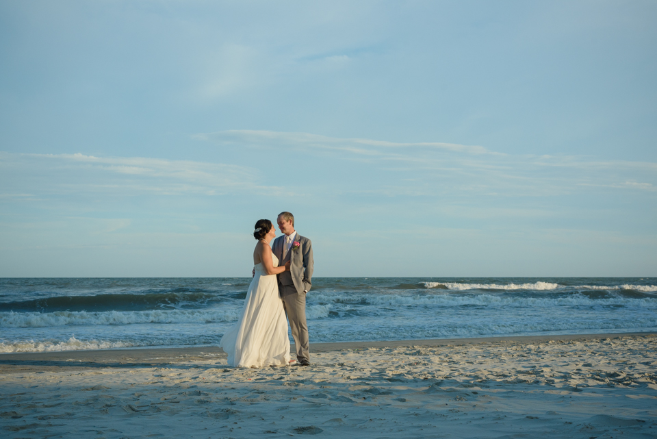 bride and groom pose on the beach for a wedding portrait