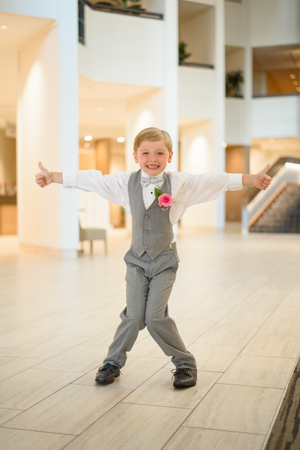 the couple's son jokes in the hotel lobby with thumbs up