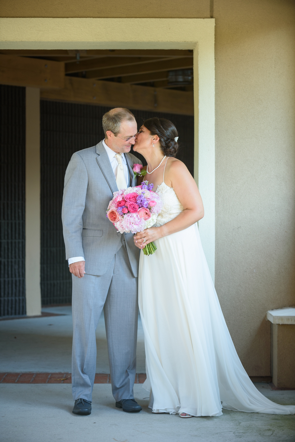 bride and groom share a first look before the wedding and bride kisses groom's cheek